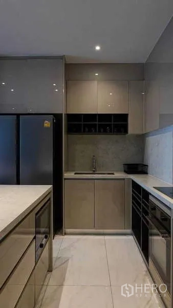 Condominium for rent or sale in Watthana, Bangkok - Modern kitchen with island, tall fridge and glossy cabinets in neutral tones.