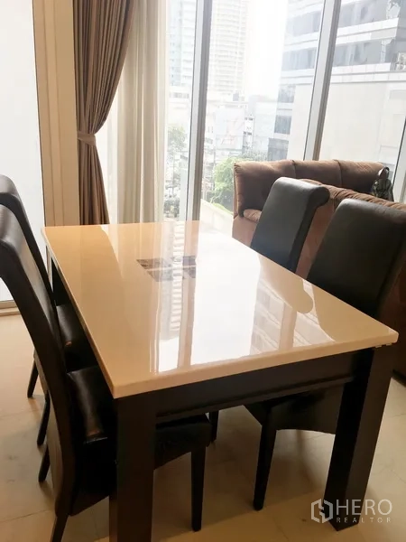 คอนโด ให้เช่าในBang Rak, Bangkok - มุมทานอาหาร โต๊ะผิวเงาพร้อมเก้าอี้สี่ตัว ข้างหน้าต่างสูงมุมมองเมือง