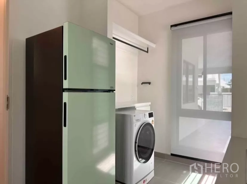 Detached House for rent in Samut Prakan - Laundry room with washing machine, shelving, and door to covered parking.