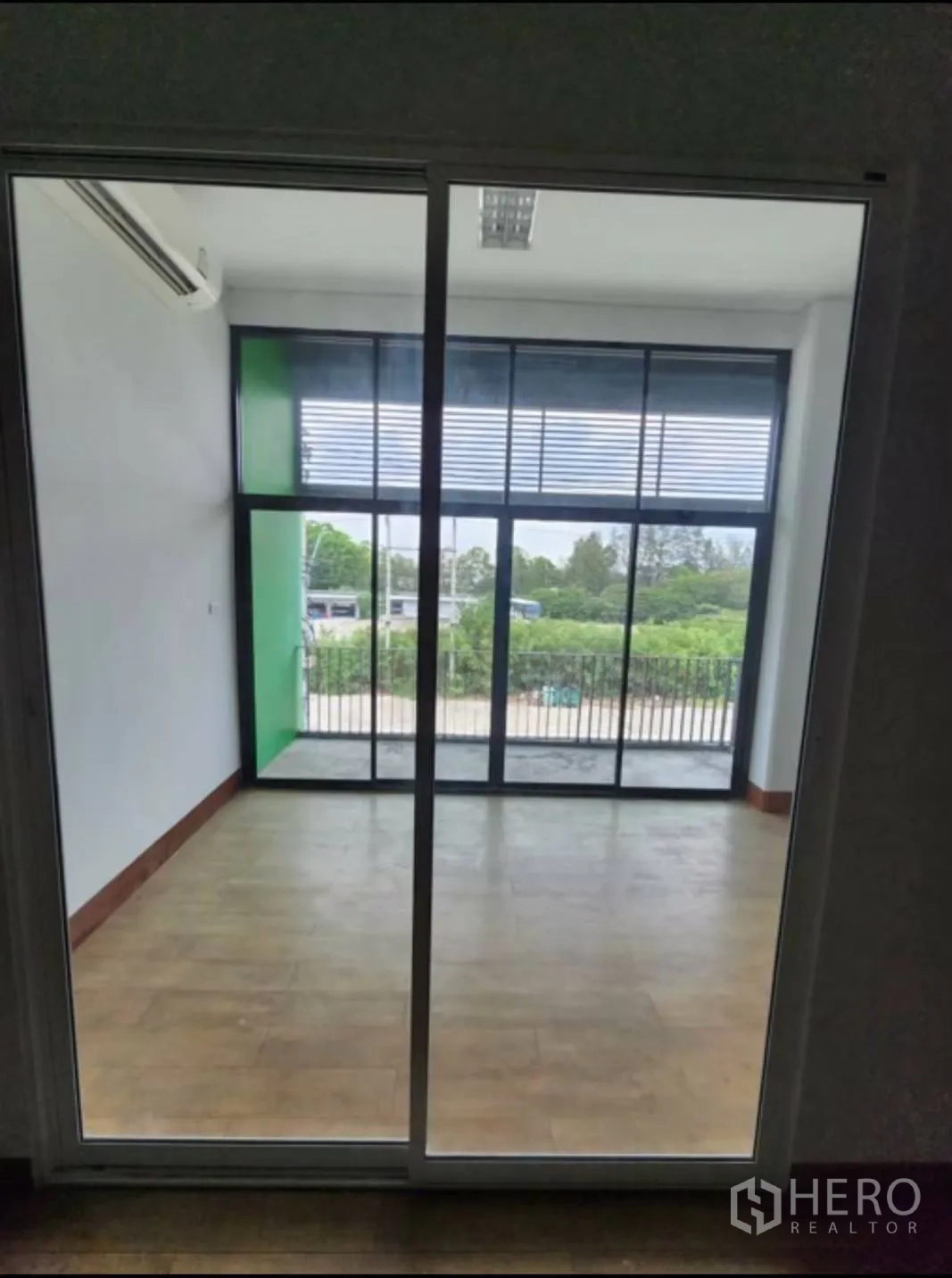 工厂 出租在Samut Prakan - 玻璃墙办公室，推拉门通向小阳台，可见绿色景观。