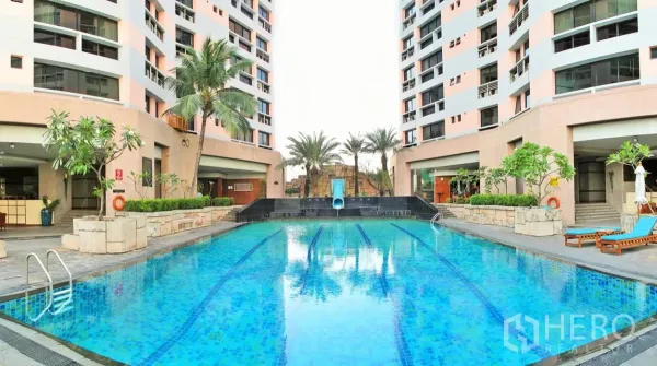 คอนโด ให้เช่าในKhlong Toei, Bangkok - สระว่ายน้ำกลางแจ้งเลนว่ายพร้อมสไลเดอร์ รายล้อมด้วยต้นปาล์มและตึกพักอาศัยในโครงการ President Park