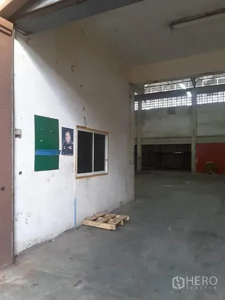 Factory for rent in Mueang Ratchaburi, Ratchaburi - Industrial factory interior with concrete floor, small office window and high ceiling near the entrance.