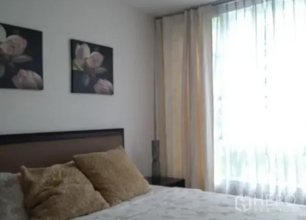 คอนโด ให้เช่าในKhlong Toei, Bangkok - ห้องนอนที่สองพร้อมหัวเตียงสีน้ำตาล รูปดอกไม้บนผนัง และหน้าต่างสูงม่านบาง