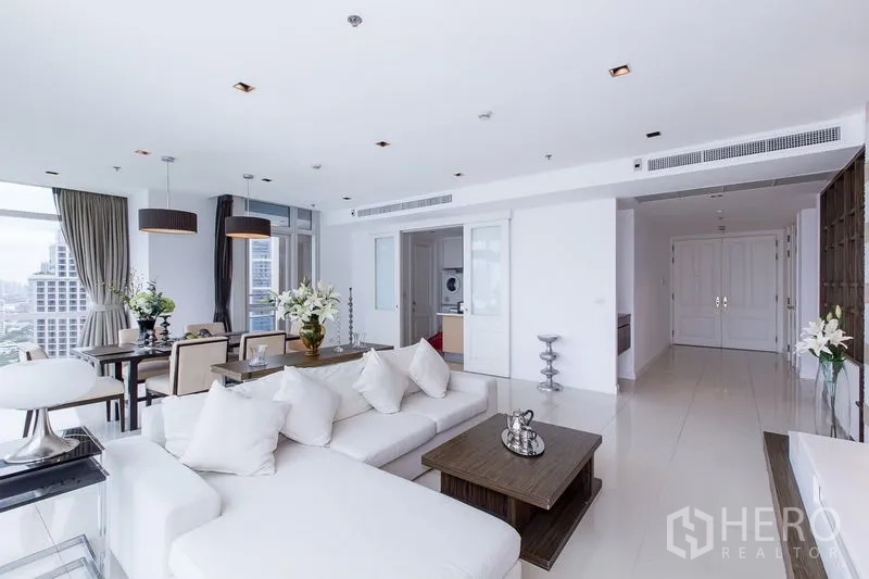 Condominium for rent in Pathum Wan, Bangkok - Living area toward dining and sliding door to kitchen, built-in shelving and white tiled floors.