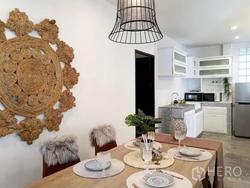 Detached House for rent in Ratchathewi, Bangkok - Dining area with woven wall art beside a clean white kitchen.