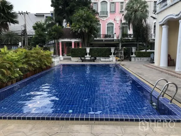 ทาวน์เฮาส์ ให้เช่าในWang Thonglang, Bangkok - สระว่ายน้ำส่วนกลางกระเบื้องสีน้ำเงิน มีบันไดสแตนเลสและต้นปาล์มจัดสวนภายในโครงการ