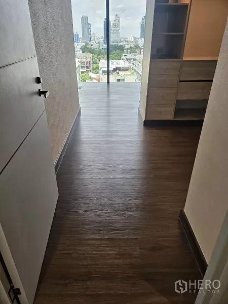 Condominium for rent in Watthana, Bangkok - Entry hallway with dark wood floors leading to a floor-to-ceiling window and Bangkok skyline view.