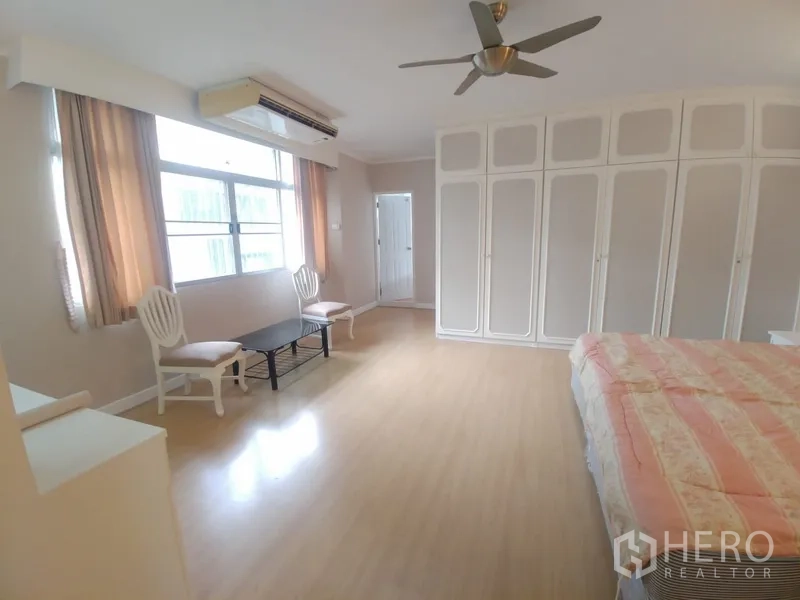 公寓 出租或出售在Watthana, Bangkok - 宽敞卧室，带大窗户、吊扇与整面嵌入式衣柜。