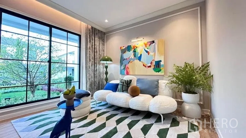 Detached House for rent or sale - Cozy sitting room with abstract art, a modern sofa and a large black-framed window looking to the garden.