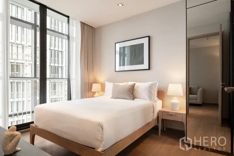 คอนโด ให้เช่า - ห้องนอนสว่างด้วยหน้าต่างเต็มบานและโคมไฟหัวเตียง