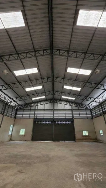 คลังสินค้า ให้เช่าในChon Buri - โครงหลังคาทรงจั่วสูงพร้อมสกายไลต์ เหนือประตูม้วนคู่ทางเข้า