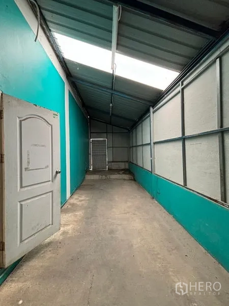 Warehouse for rent in Phra Samut Chedi, Samut Prakan - Covered side corridor/loading area with metal roof and teal walls.