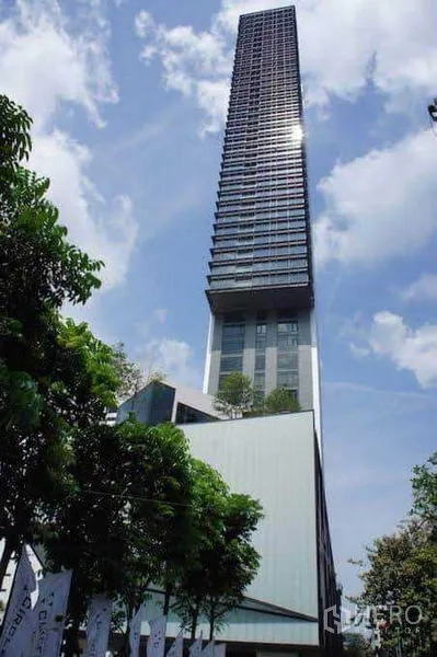 Condominium for rent in Ratchathewi, Bangkok - Exterior of a modern high-rise condominium tower against blue sky and trees.