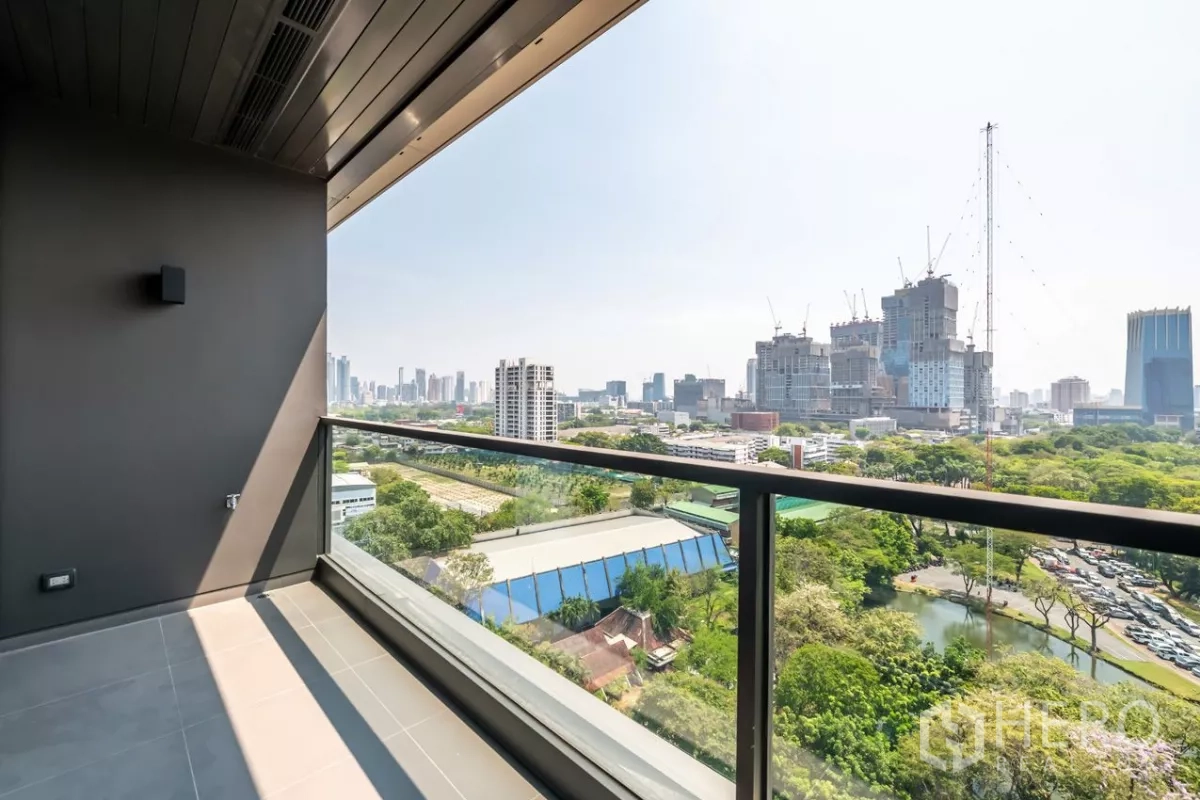 Condominium for rent or sale in Pathum Wan, Bangkok - Covered balcony with glass railing and far-reaching views over park and skyline.