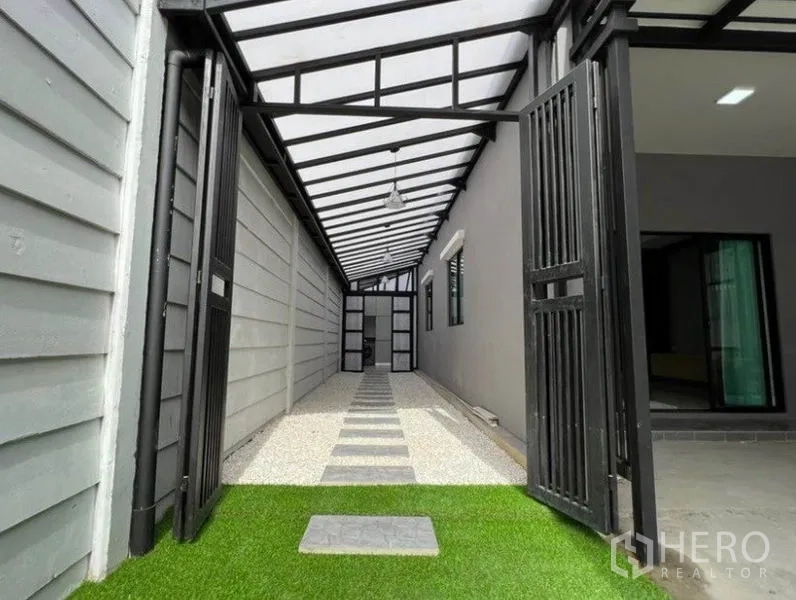 ทาวน์เฮาส์ ให้เช่าในWang Thonglang, Bangkok - ทางเดินด้านข้างติดหลังคาโครงเหล็ก มีประตูเหล็กและสนามหญ้าเทียม