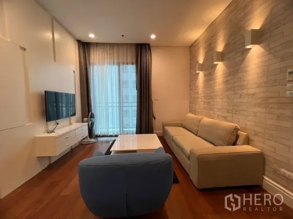 คอนโด ให้เช่าในKhlong Toei, Bangkok - พื้นที่นั่งเล่นผนังลายอิฐตกแต่ง โซฟา โต๊ะกลาง และทางออกสู่ระเบียง