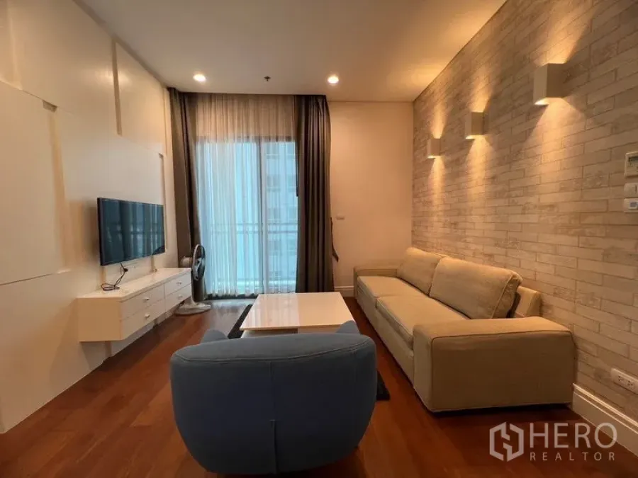 公寓 出租在Khlong Toei, Bangkok - 带砖纹特色墙的客厅，配沙发、茶几与阳台出入口。