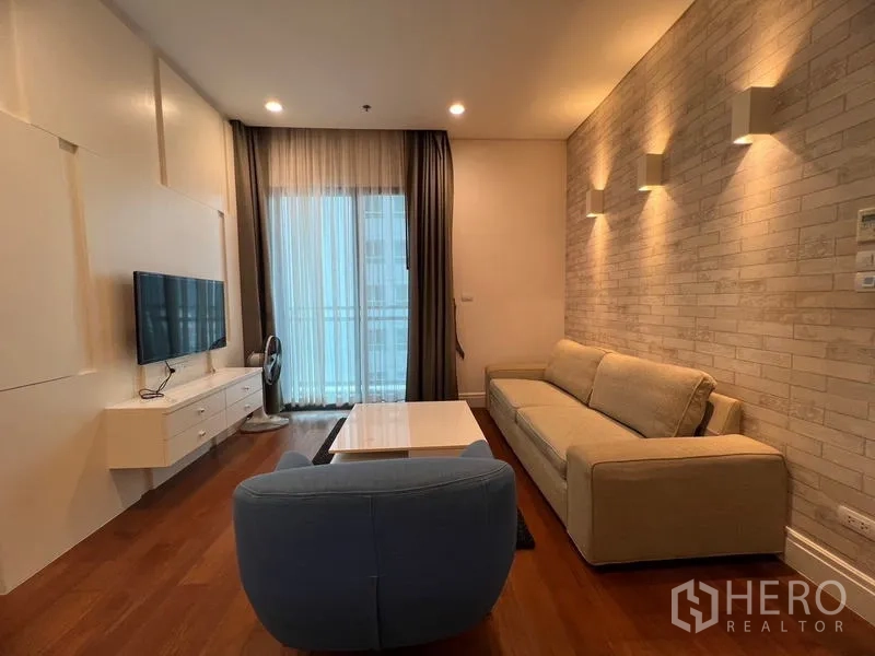 公寓 出租在Khlong Toei, Bangkok - 带砖纹特色墙的客厅，配沙发、茶几与阳台出入口。