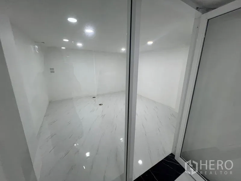 Office Space for rent or sale in Wang Thonglang, Bangkok - Glass-partitioned meeting room with white marble-look tile and recessed lighting.