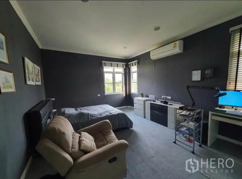 独立式住宅 出售在Sai Mai, Bangkok - 宽敞卧室，深色墙面，书桌、大窗与空调。