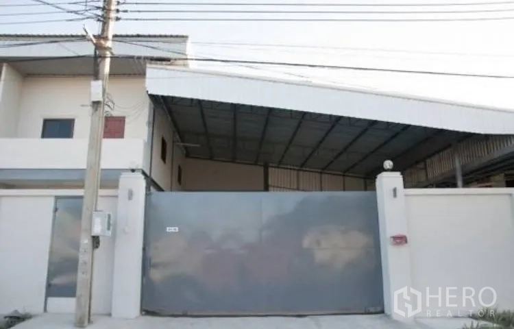 Warehouse for rent in Bang Phli, Samut Prakan - Street-side entrance with tall metal sliding gate and perimeter wall.
