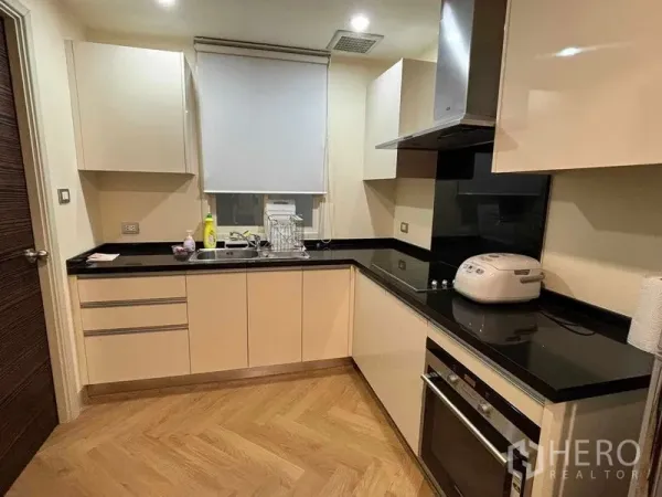 คอนโด ให้เช่า - ครัวรูปตัว U ท็อปหินแกรนิตสีดำ มีเตาอบและเครื่องดูดควัน