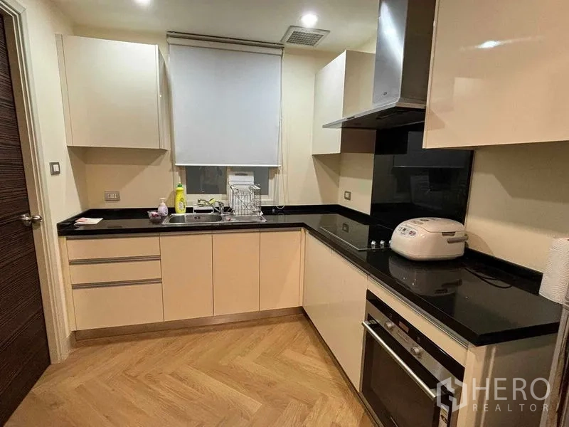 คอนโด ให้เช่า - ครัวรูปตัว U ท็อปหินแกรนิตสีดำ มีเตาอบและเครื่องดูดควัน