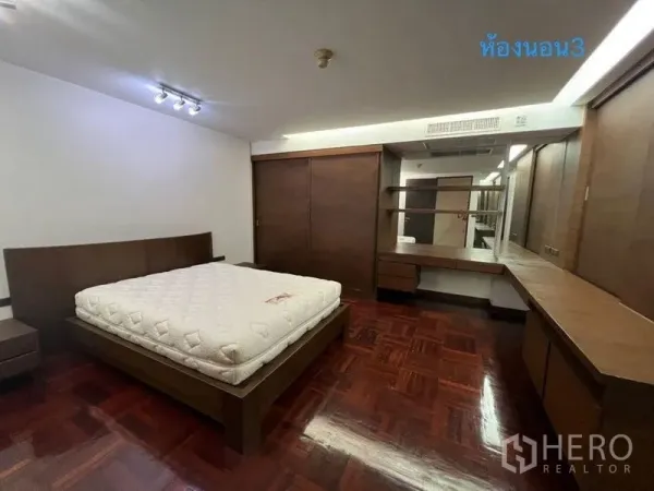 公寓 出租在Khlong Toei, Bangkok - 宽敞卧室，配特大床、深色木质衣柜、梳妆台和亮面拼花地板