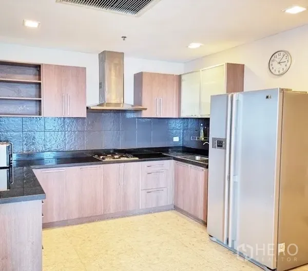 公寓 出租在Khlong Toei, Bangkok - 现代L型厨房，木质橱柜、黑色台面，配抽油烟机与大号不锈钢冰箱。