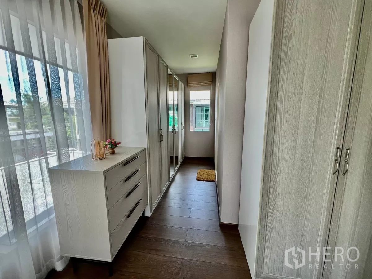 Detached House for rent or sale in Bang Phli, Samut Prakan - Walk-in closet corridor lined with wardrobes and a dresser by the window.