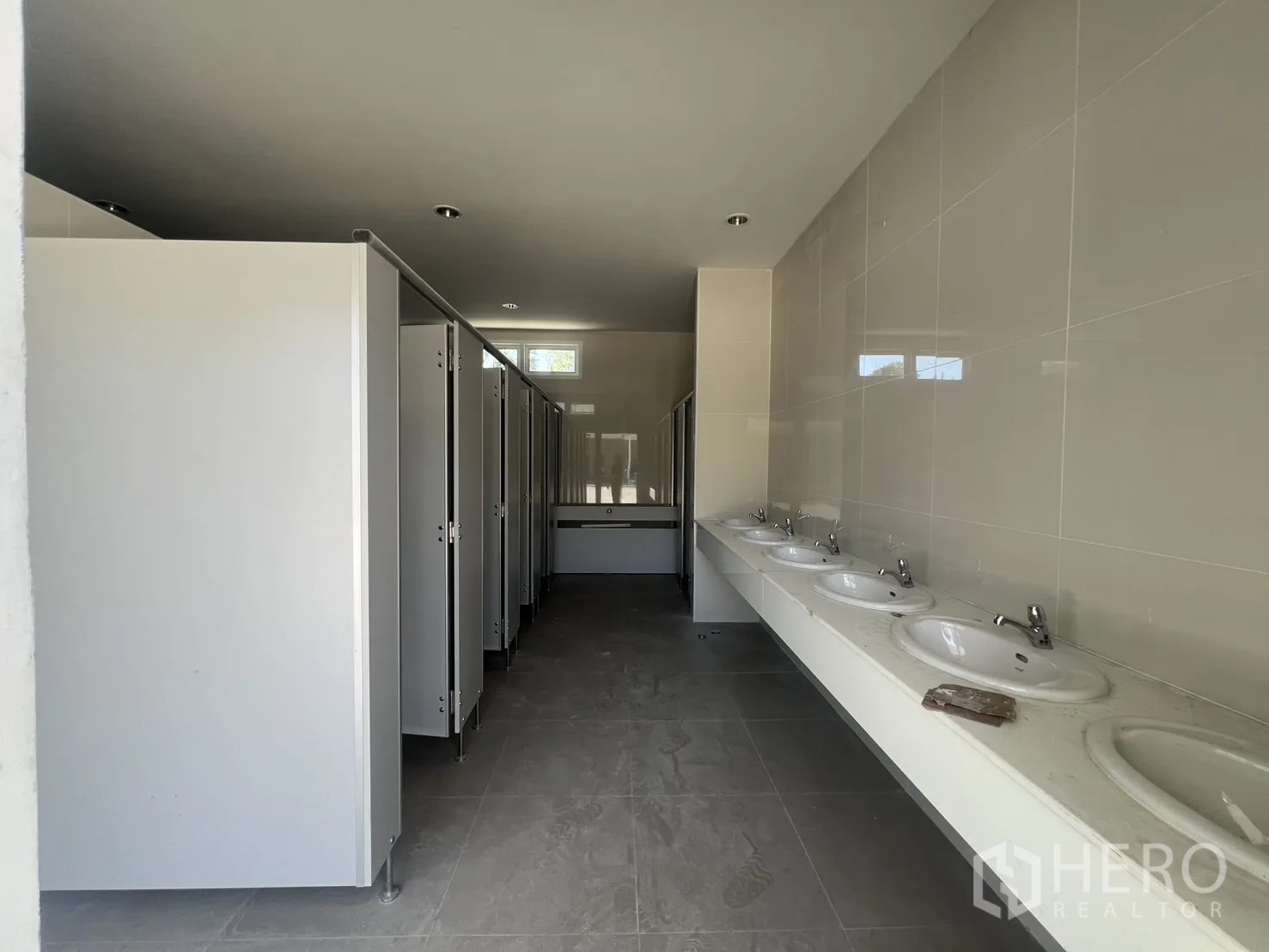 Warehouse for rent in Min Buri, Bangkok - Newly tiled restroom with multiple basins and enclosed stalls for staff.