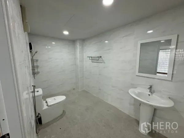Home Office for rent in Bueng Kum, Bangkok - Renovated bathroom with marble-style tiles, toilet, walk-in shower and pedestal sink.