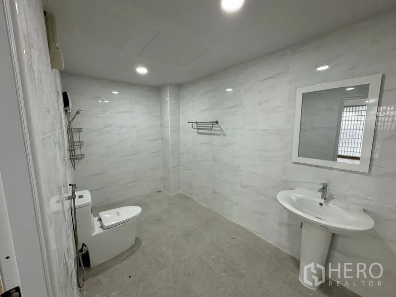Home Office for rent in Bueng Kum, Bangkok - Renovated bathroom with marble-style tiles, toilet, walk-in shower and pedestal sink.