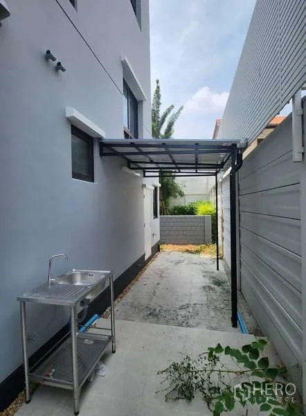 Detached House for rent in Wang Thonglang, Bangkok - Side yard and service area with stainless sink, canopy roof and paved walkway.