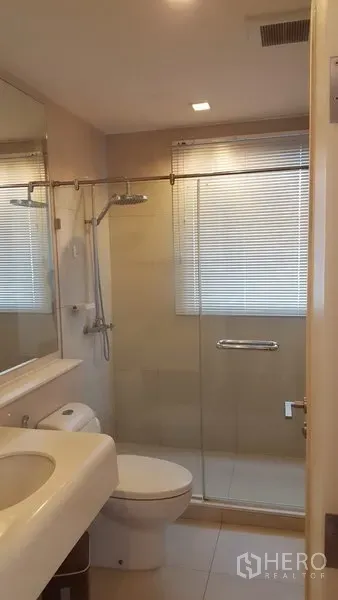 公寓 出租在Bang Rak, Bangkok - 现代卫浴，玻璃干湿分离淋浴间、台盆与马桶，窗配百叶帘。