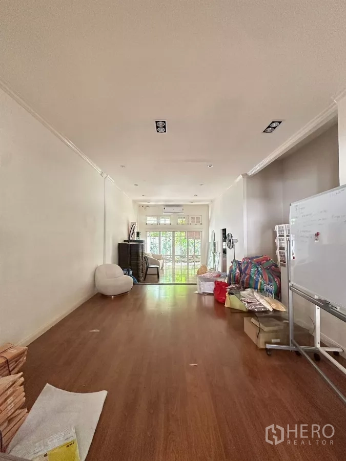 ทาวน์เฮาส์ ให้เช่าในWatthana, Bangkok - ห้องโล่งยาว พื้นลามิเนต ไฟดาวน์ไลท์ และประตูกระจกออกสู่ระเบียง