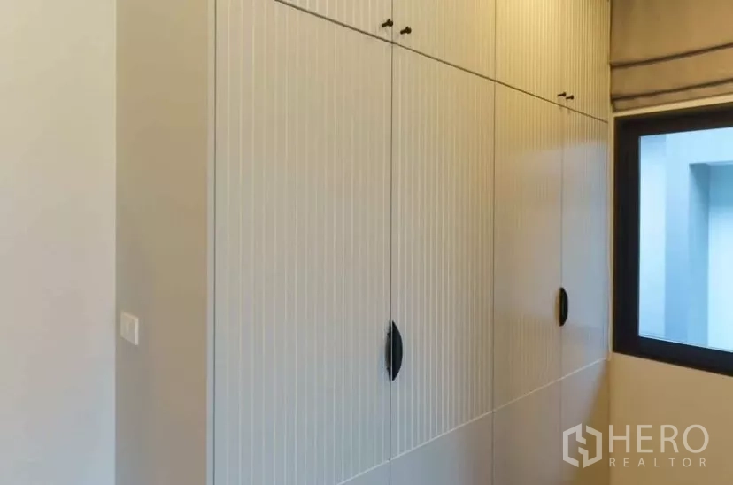 Detached House for rent or sale in Bang Phli, Samut Prakan - Close-up of full-height built-in wardrobes with vertical groove detailing.
