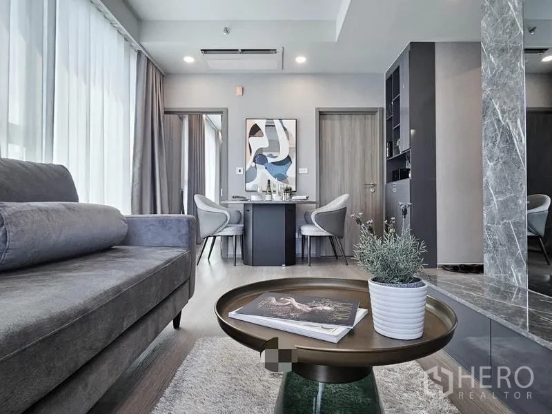 Condominium for rent in Samut Prakan - Open living and dining zone with round coffee table and bright windows.