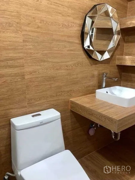 Home Office for rent or sale in Pak Kret, Nonthaburi - Guest bathroom with wood-grain walls, floating vanity and a faceted round mirror.