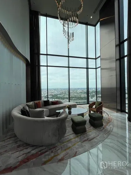 公寓 出租在Ratchathewi, Bangkok - 双层挑高的空中会所，吊灯与弧形沙发，俯瞰曼谷。