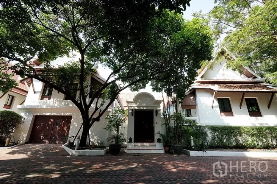 บ้าน ให้เช่าในWatthana, Bangkok - ด้านหน้าบ้านเดี่ยวสไตล์ไทย มีโรงรถ ต้นไม้ใหญ่ และทางรถเข้าปูอิฐ