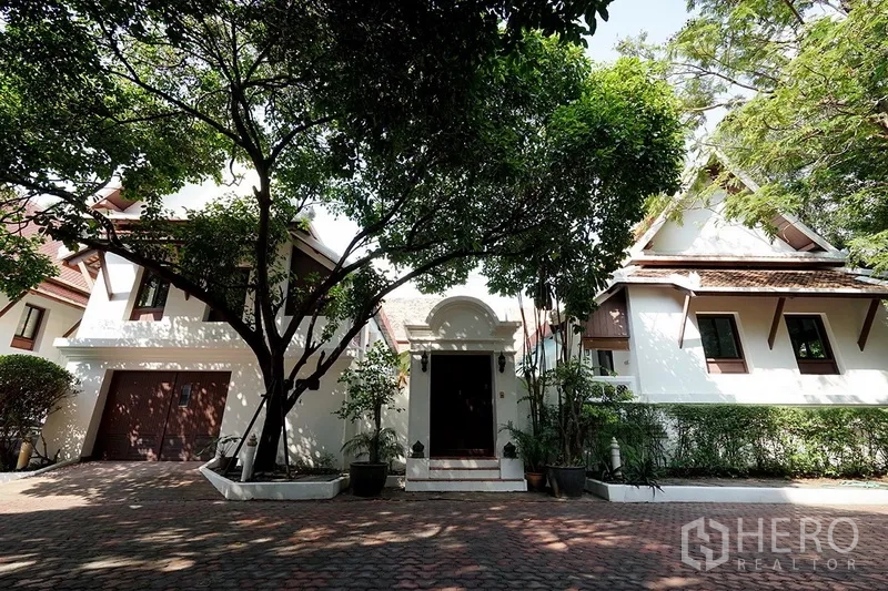 บ้าน ให้เช่าในWatthana, Bangkok - ด้านหน้าบ้านเดี่ยวสไตล์ไทย มีโรงรถ ต้นไม้ใหญ่ และทางรถเข้าปูอิฐ