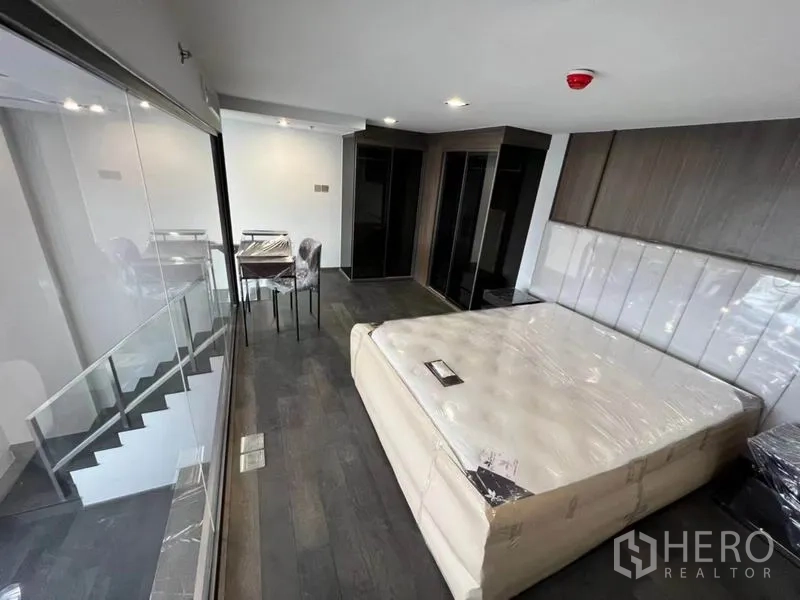 公寓 出租在Ratchathewi, Bangkok - 夹层卧室俯视客厅，玻璃护栏与内置衣柜。