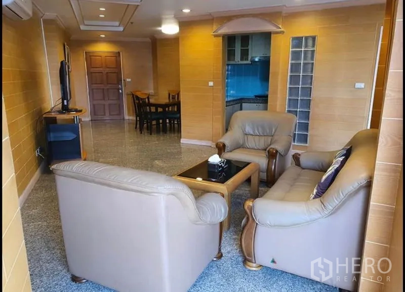 Condominium for rent in Ratchathewi, Bangkok - Spacious living room with leather sofa set, TV and granite floors in a Bangkok condo.