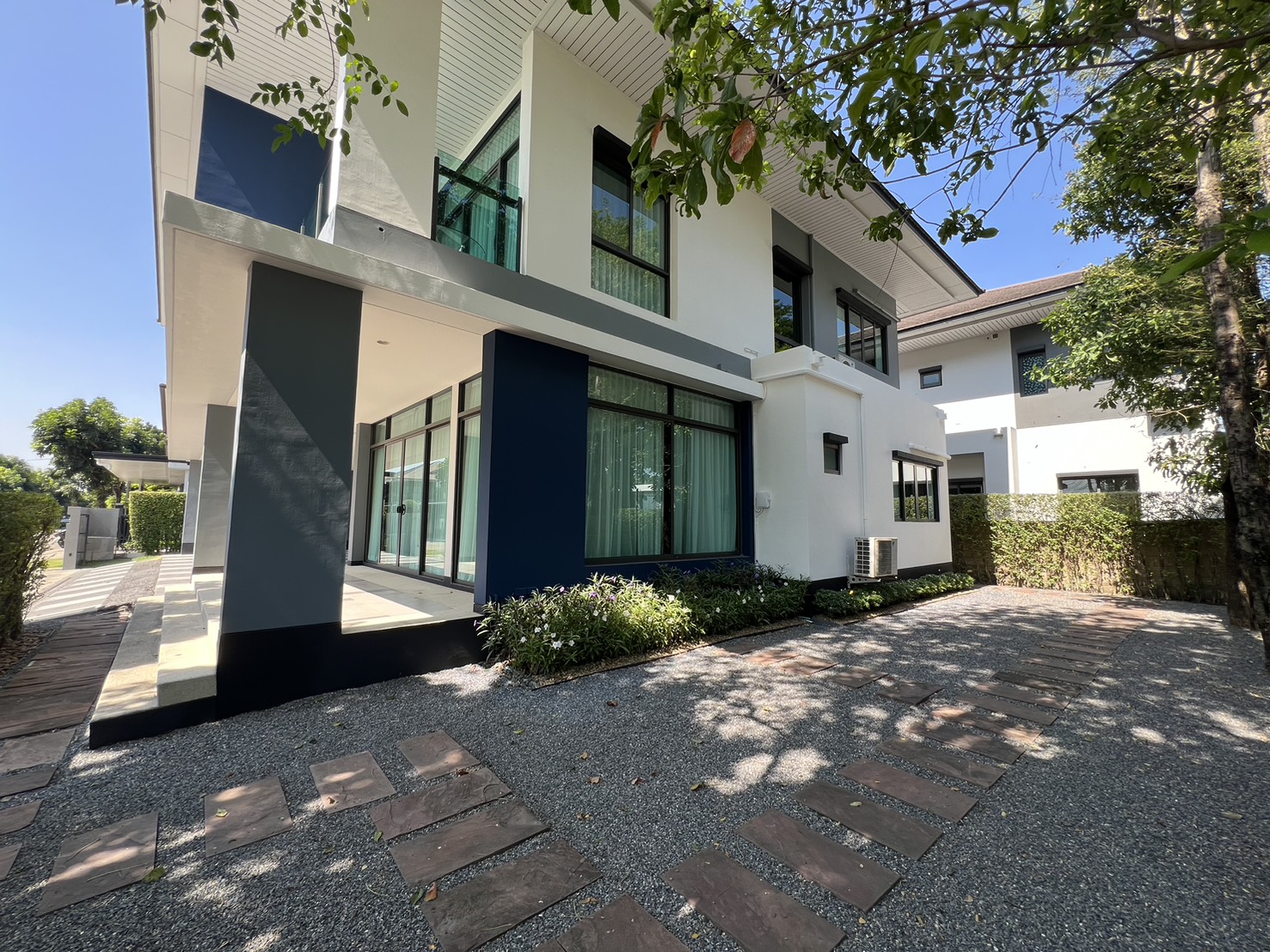 Detached House for rent in Bang Kapi, Bangkok - Side exterior with floor-to-ceiling windows, garden path and mature trees.