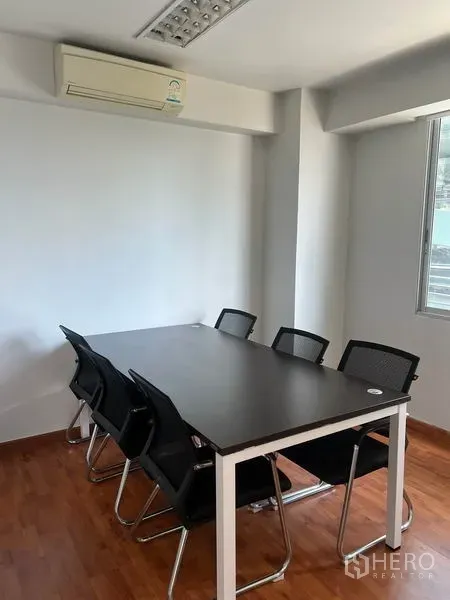 Office Space for rent in Khlong Toei, Bangkok - Compact meeting room with black table, mesh chairs, window and wall-mounted air conditioner.