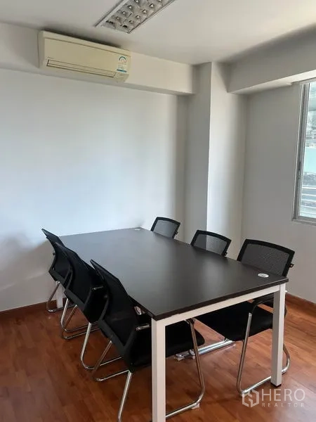 Office Space for rent in Khlong Toei, Bangkok - Compact meeting room with black table, mesh chairs, window and wall-mounted air conditioner.