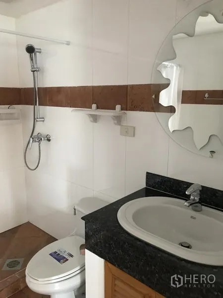 Condominium for rent in Watthana, Bangkok - White bathroom with handheld shower, toilet and a granite-top vanity.