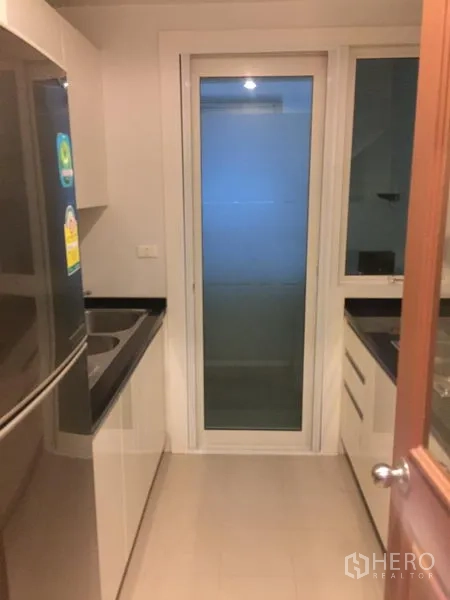 คอนโด ให้เช่าหรือขายในKhlong Toei, Bangkok - ครัวปิดสไตล์โมเดิร์น เคาน์เตอร์หินสีดำ อ่างล้างจาน ตู้เย็น และประตูกระจกบานสไลด์