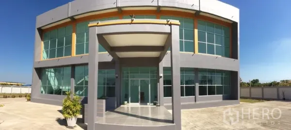 โรงงาน ขายในBang Sao Thong, Samut Prakan - ทางเข้าอาคารพร้อมกันสาดและผนังกระจกสูงจรดเพดานของส่วนสำนักงาน.